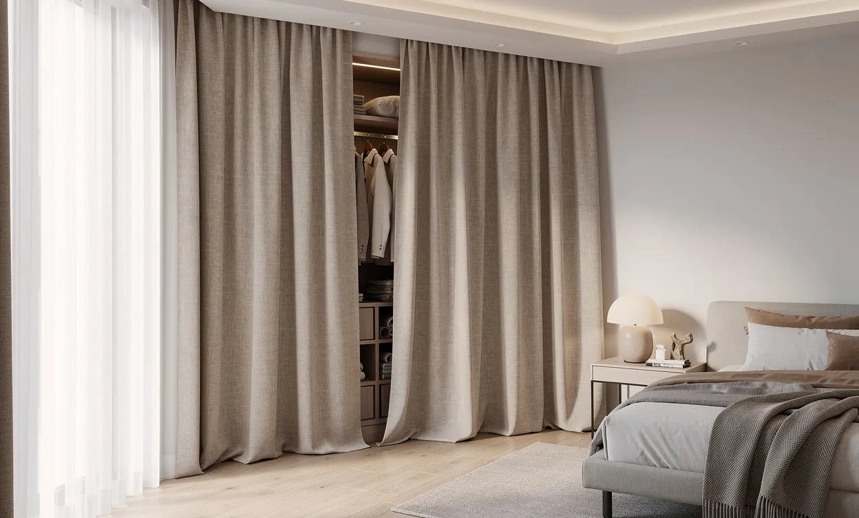 Coin de chambre moderne avec un rideau en lin du sol au plafond dissimulant un espace dressing organisé, baigné de lumière naturelle et aux couleurs neutres.