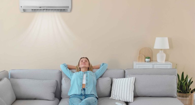 Femme détendue sur canapé sous climatiseur mural dans salon moderne