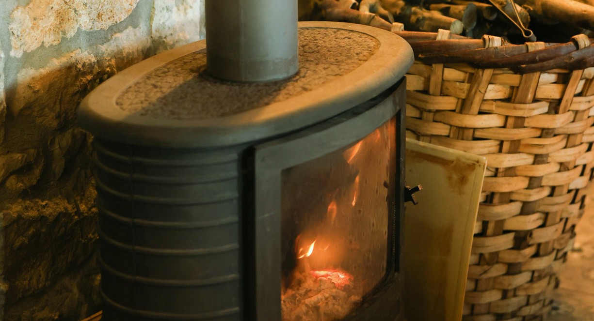 Cheminee en pierre avec un feu de bois et plaque de fonte au fond du foyer