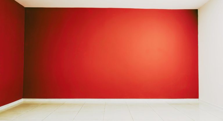 Piece vide avec un mur peint en rouge profond et sol carrele clair