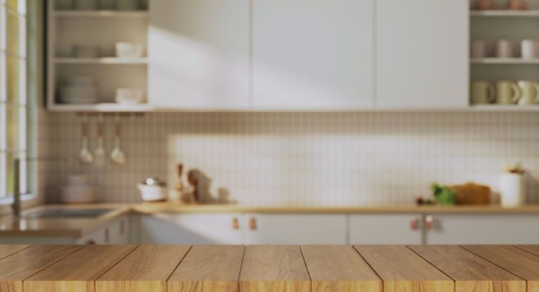 Plan de travail en bois clair posé devant un fond de cuisine blanche
