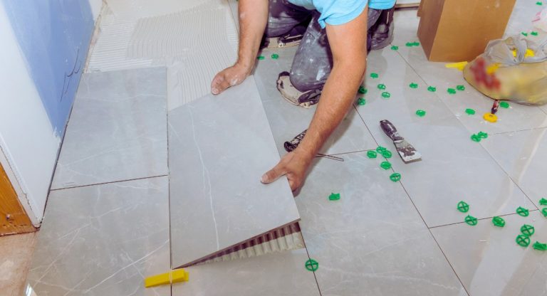 Mains posant des carreaux ceramiques sur une couche de colle