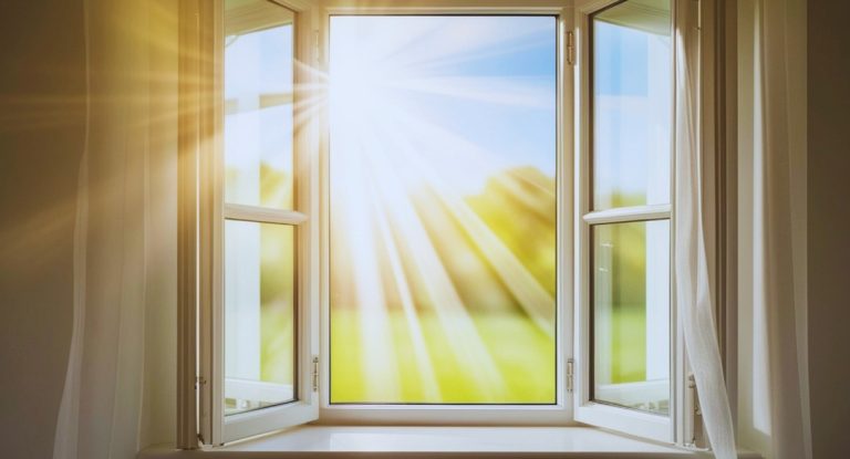 Fenêtre ouverte habillée de voilages blancs laissant entrer la lumière naturelle dans une pièce