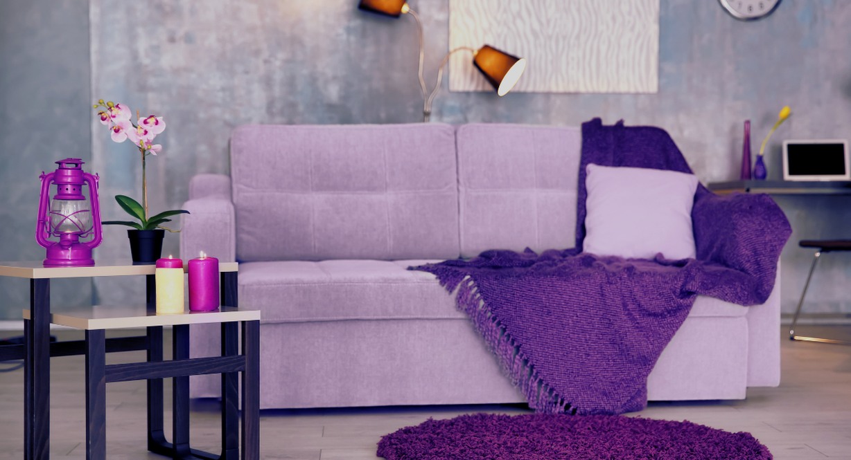 Canapé parme avec plaid violet et accessoires de décoration assortis