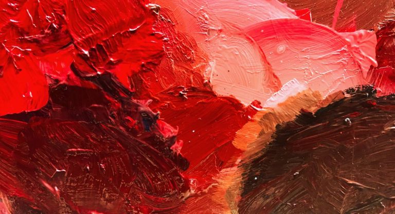 Gros plan sur de la peinture rouge mélangée avec des nuances sur une palette d'artiste