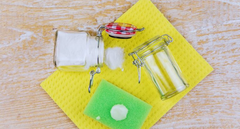 Bocaux de poudre nettoyante et eponge verte avec une noisette de pate blanche