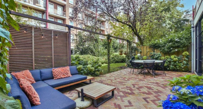 Patio de jardin moderne avec canapé d'extérieur, table à manger et végétation
