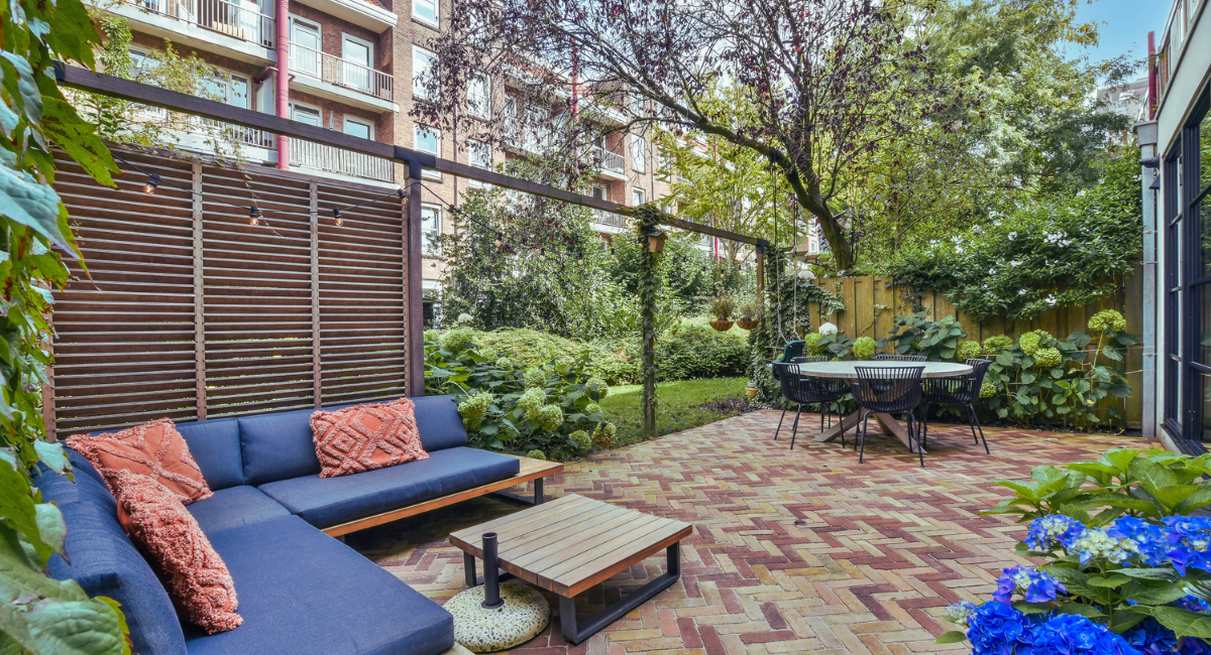Patio de jardin moderne avec canapé d'extérieur, table à manger et végétation