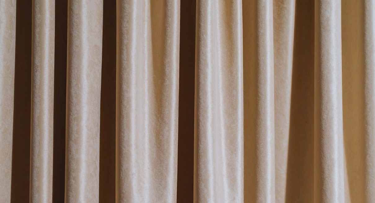Gros plan sur un tissu de rideau en velours beige aux plis verticaux