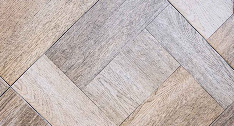 Lames de carrelage imitation parquet aux tons gris et beige posées en diagonale