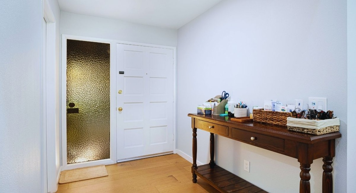 Console en bois foncé à deux tiroirs et paniers de rangement dans une entrée claire près de la porte
