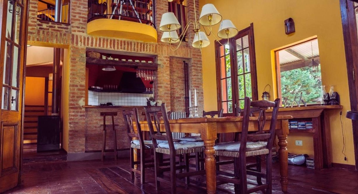 Salle à manger rustique aux murs de brique avec une grande table en bois et ses chaises paillées